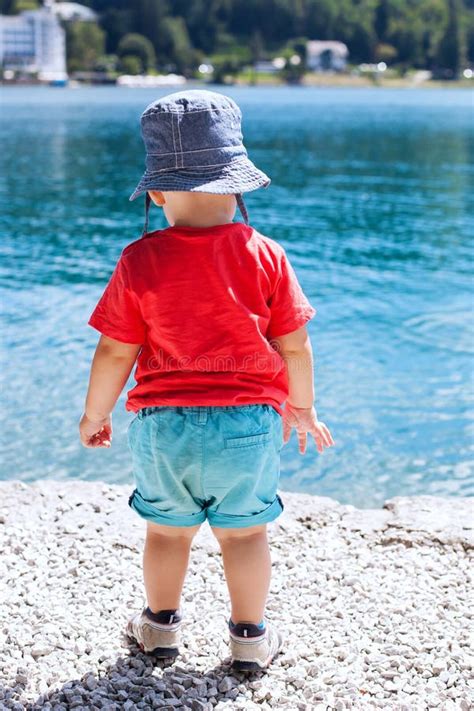 Child In Summer Clothes On A Background Of The Bright Blue Water Stock