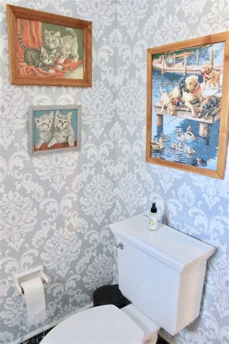 a bathroom with two pictures on the wall and a toilet in front of it,