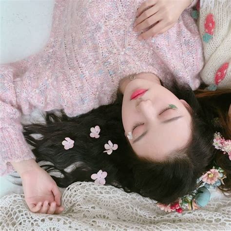 A Woman Laying On Top Of A Bed With Her Eyes Closed And Flowers In Her Hair