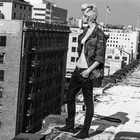 A Woman Standing On Top Of A Roof Next To Tall Buildings In Black And White