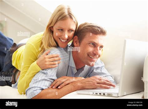 Couple Using Laptop Relaxing Sitting On Sofa At Home Stock Photo Alamy