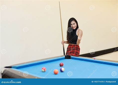 Beautiful And Asian Woman In Black Dress Playing Billiard Or Snooker On
