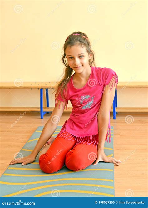 A Ten Year Old Girl Sits On A Gymnastics Mat In A Gym Stock Photo