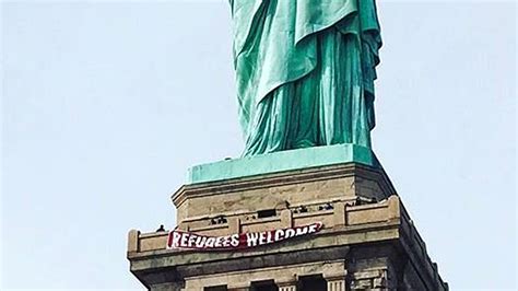 refugees welcome banner unfurled at statue of liberty