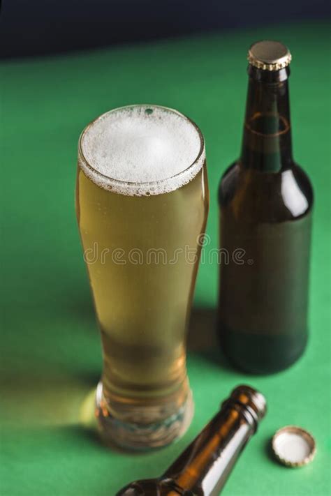 Two Dark Beer Bottles A Glass Of Beer And Foam And A Plate Of