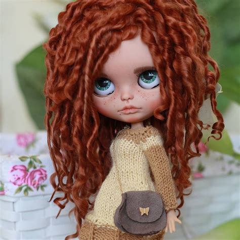 A Close Up Of A Doll With Red Hair And Blue Eyes Wearing A Brown Sweater