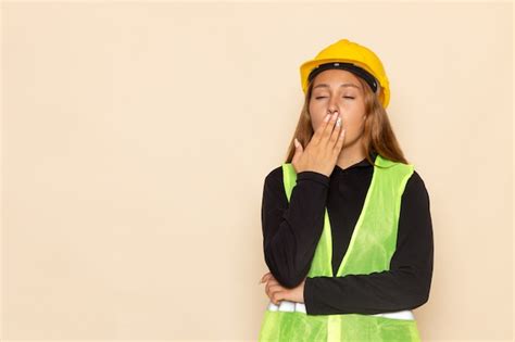 Free Photo Front View Female Builder In Yellow Helmet Black Shirt Posing Yawning On The White Wall
