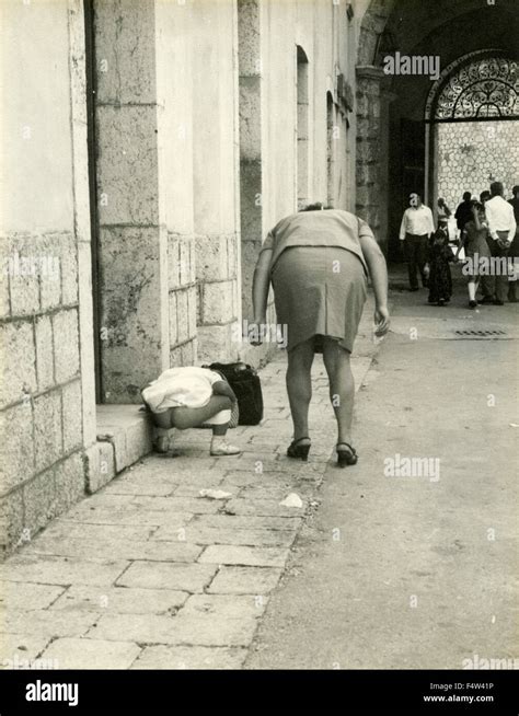 Una Chica Orinando En La Calle Mientras Que La Madre Observa Italia Fotografía De Stock Alamy