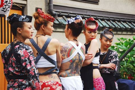 Several Women With Tattoos Standing Next To Each Other