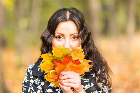 Young Woman With Autumn Leaves In Hand And Fall Yellow Maple Garden