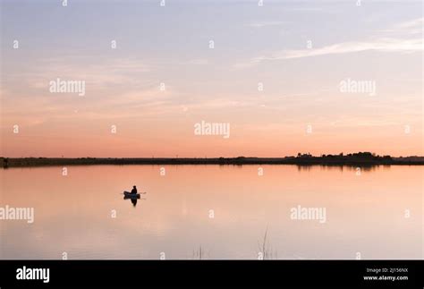 Fisherman Floating On The Still Lake During Sunset Stock Photo Alamy