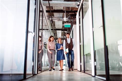 Group Of Business People Walking In An Office Building Talking Stock