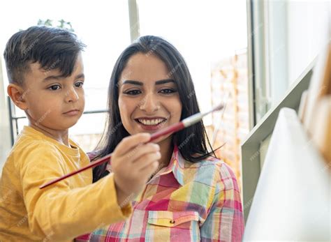 Madre Hispana Latente Enseñando A Su Hijo A Pintar Un Cuadro En Casa