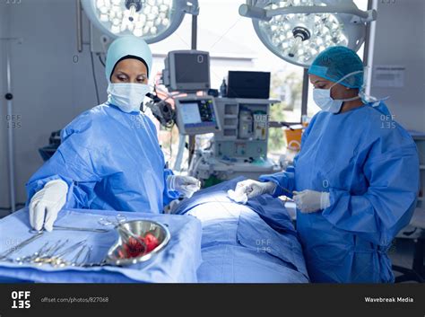 Side View Of Diverse Female Surgeons Performing Surgery In Operation Room At Hospital Stock