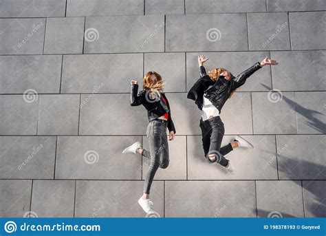 duas belas namoradas adolescentes pulam e se divertem perto da parede cinza de concreto tempo