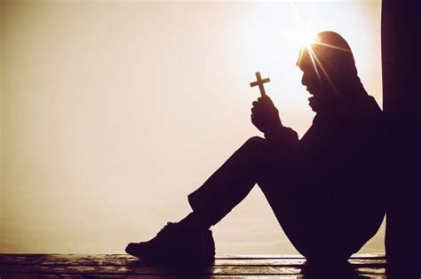 Download Silhouette Of A Man Praying With A Cross In Hand At Sunrise