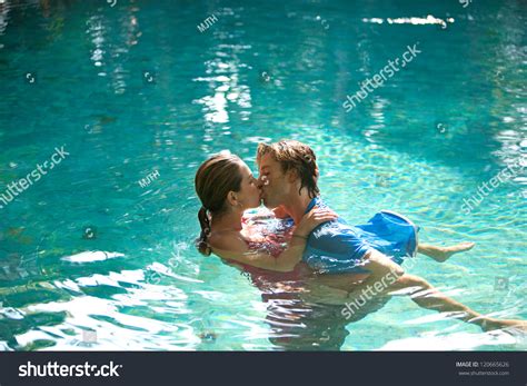 Sexy Young Couple Submerged In A Swimming Pool While Dressed Hugging And Kissing While On A