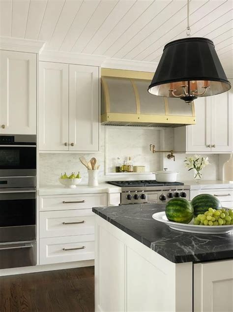 Well Appointed White And Gold Kitchen Features A Black Drum Light