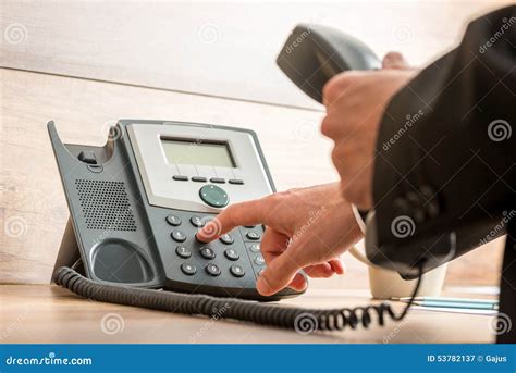 Businessman Hand Holding A Landline Telephone Receiver Dialing A Stock