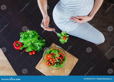 Pregnant Woman In Kitchen Is Eating Vegetable Salad Stock Image
