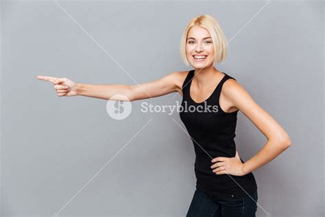 Cheerful Beautiful Young Woman Pointing Away Over Gray Background