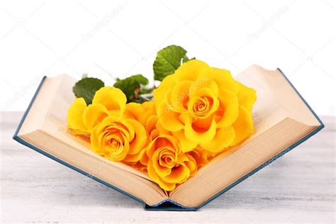 Selecciona tu libro de segundo grado de secundaria. Yellow roses with open book on wooden table isolated on white — Stock Photo © belchonock #66908029