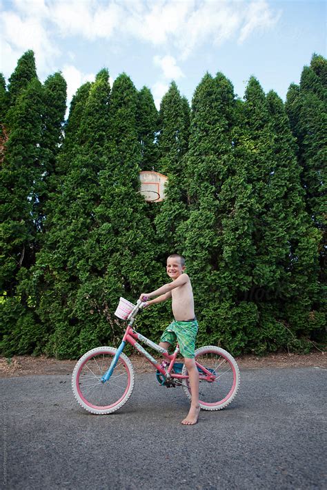 Barefoot Shirtless Boy On Bike In Front Of Basketball Hoop Stocksy