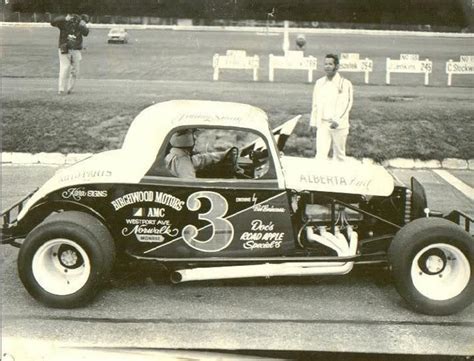 An Old Race Car With The Number Three On It And Two Men Standing Next To It