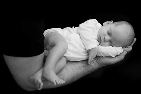 Father Holding Sleeping Newborn Baby On His Hand On Black Background