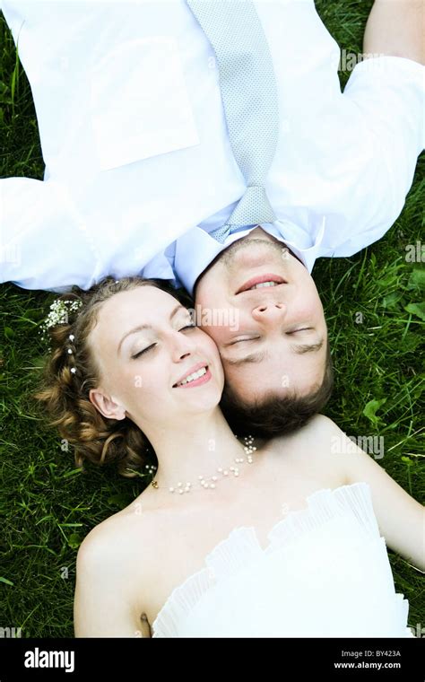 View From Above Of Happy Newlyweds Lying On Green Grass And Touching