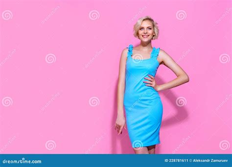 Portrait Of Beautiful Blonde Woman In Blue Dress Posing On Pink Studio