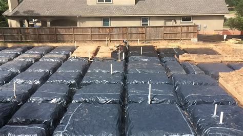 Plastic foundation pins are hammered into the holes to carry the weight of the vapor barrier. Covering with anti barrier plastic the foundation blocks ...