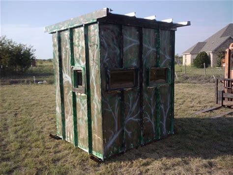 An Outhouse In The Middle Of A Field With Graffiti On It