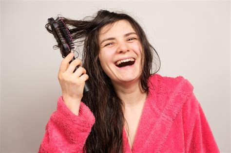 Premium Photo A Woman In A Pink Robe Combs Her Wet Hair With A Comb