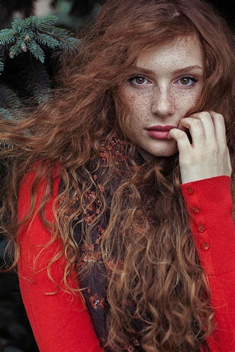 A Woman With Long Red Hair And Freckles On Her Face Posing For The Camera