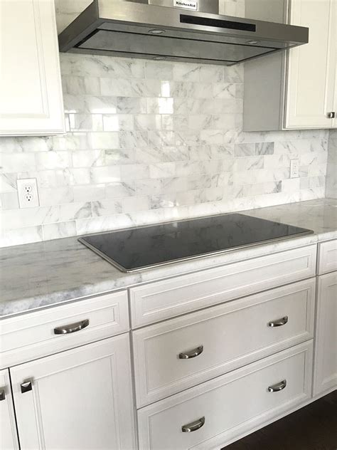 Spacious kitchen with black cabinets, stainless appliances, tile backsplash and super white marble countertops. Carrera Marble Subway Tile Backsplash with white cabinets ...