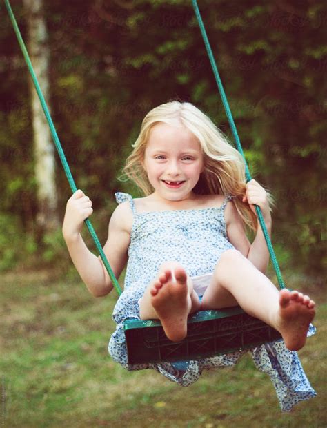 A Blonde Haired Little Girl With Missing Teeth On A Swing Del