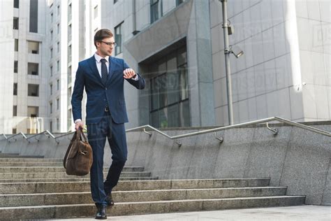 Attractive Young Businessman In Stylish Suit With Briefcase Looking At
