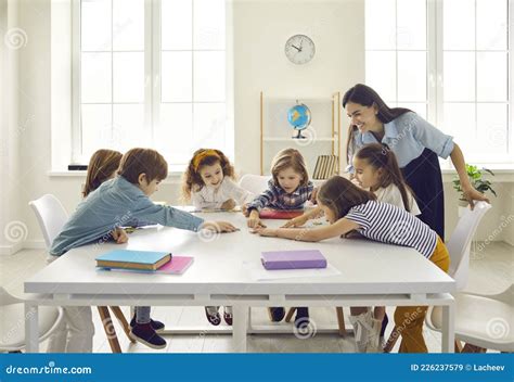 Happy School Teacher And Little Children Having A Class And Learning