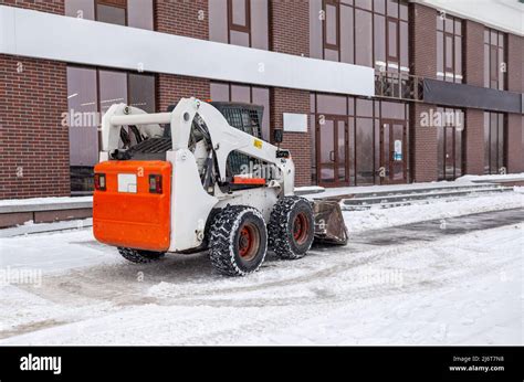Small Snow Removal Vehicle Removing Snow On City Square Yellow Or