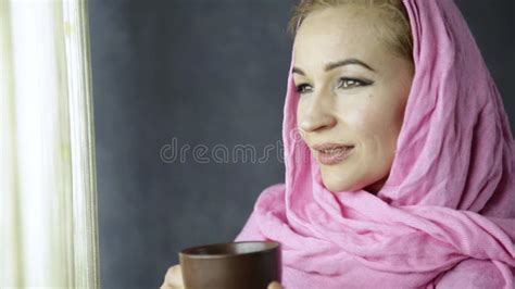 beautiful arabian woman in pink hijab sitting on a sofa in a cafe and drinks cofee stock footage