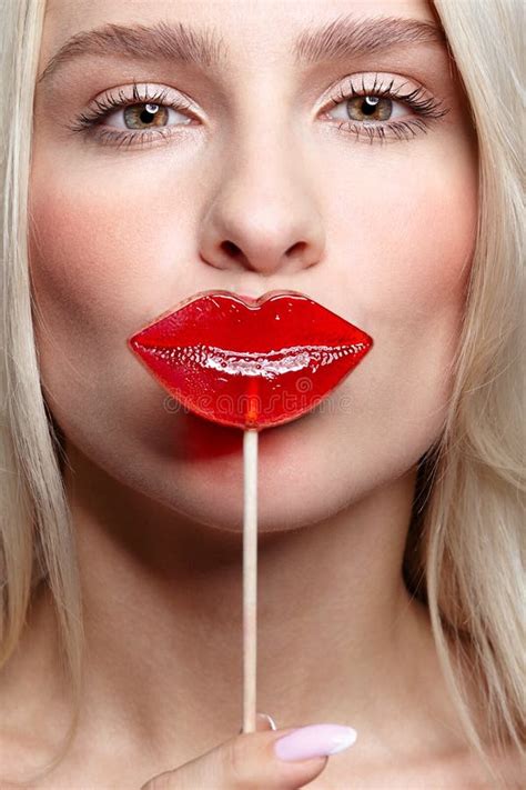 Portrait Of Blonde Woman Kissing Candy Red Female Lips Shape Lollipop