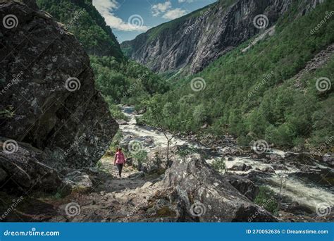 Woman Hiking Along River In The Valley Of Voringsfossen Waterfall At