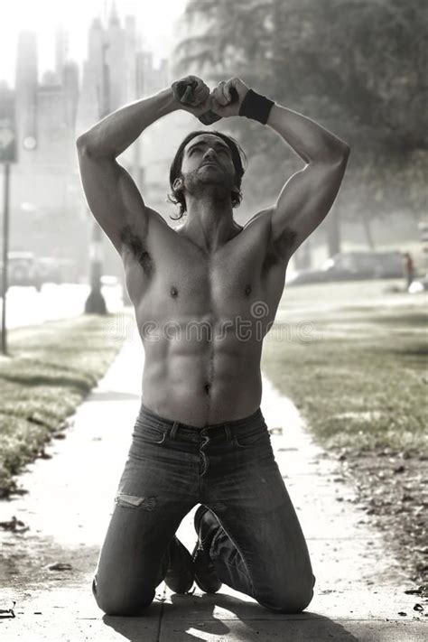 A Shirtless Man Sitting On The Sidewalk With His Hands Up To His Head