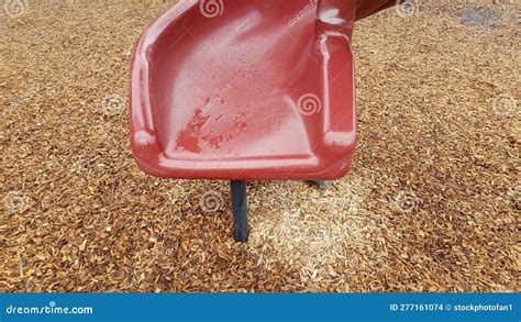 Red Plastic Playground Slide With Wood Chips On Ground Stock Photo