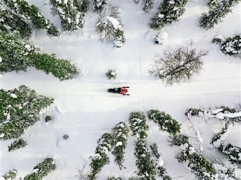 premium photo aerial view of red snowmobile in snow covered winter forest in rural finland lapland