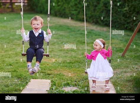 Little Boy And Girl Ride In The Park On A Swing Stock Photo Alamy