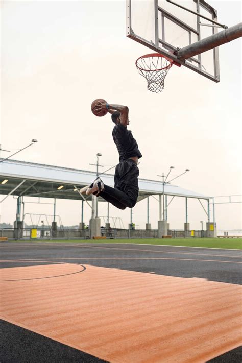 Side View Of Man Scoring While Practicing Basketball In Court Against