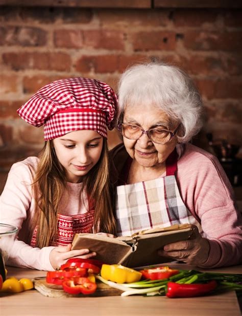 premium photo little granddaughter reading recipe book with her granny sitting at kitchen