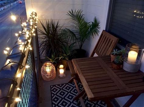 An Outdoor Patio With Lights And Plants On The Balcony Railing Along